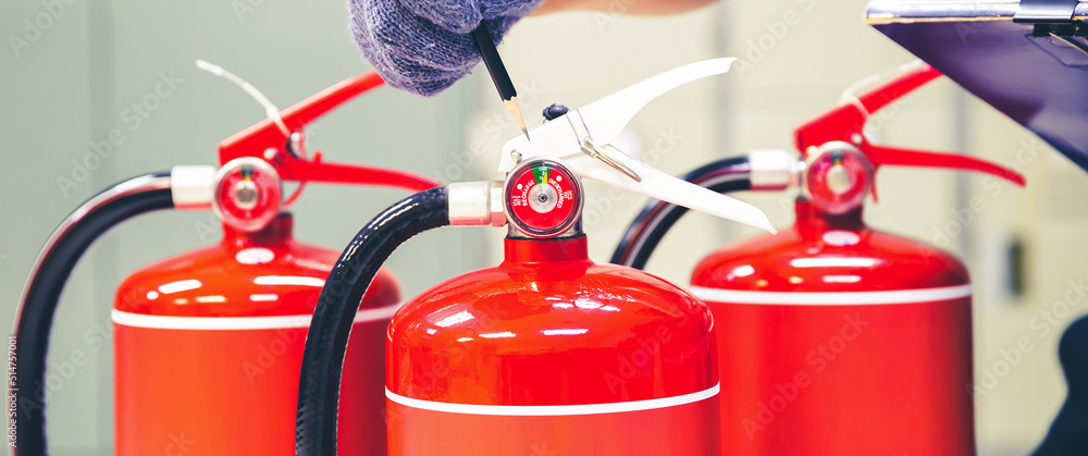 Fire extinguisher has hand engineer inspection checking pressure gauges to prepare fire equipment for protection and prevent in emergency case and safety or rescue and alarm system training concept.