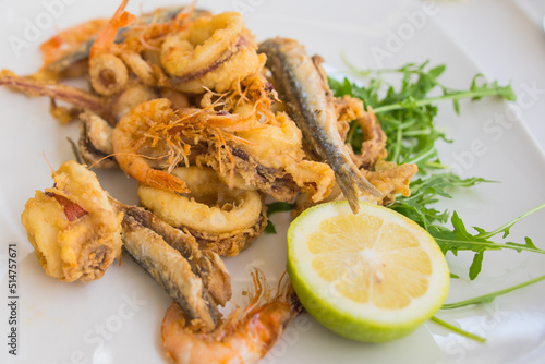 Fried local seafood (Fritto misto di mare or Fritto misto di pesce ) squid rings, prawns, sardines, and octopus, with lemon on white plate. Popular food in Sicily.  photo