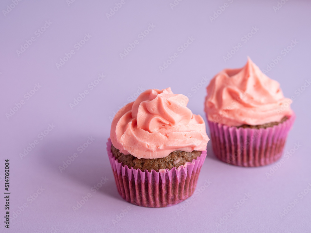 Two cupcakes on a purple background with a side light and a place for text Two cupcakes on a purple background with a side light and a place for text