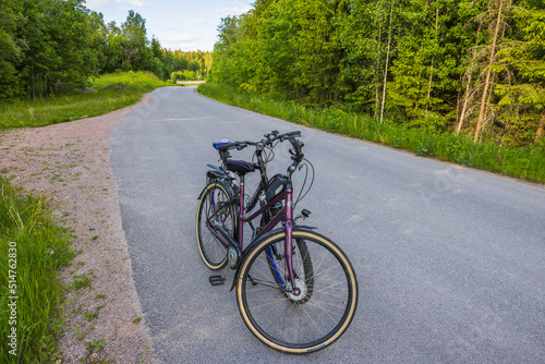 Close up view of two bicycles isolated on asphalt road with forest landscape on background. Sweden.
