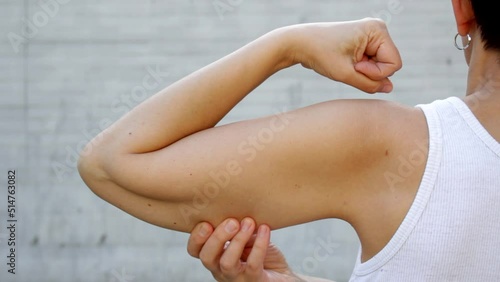 Faceless woman showing flabby arm muscles . Saggy arm syndrome (SAD). Loss of muscle elasticity caused by aging. photo