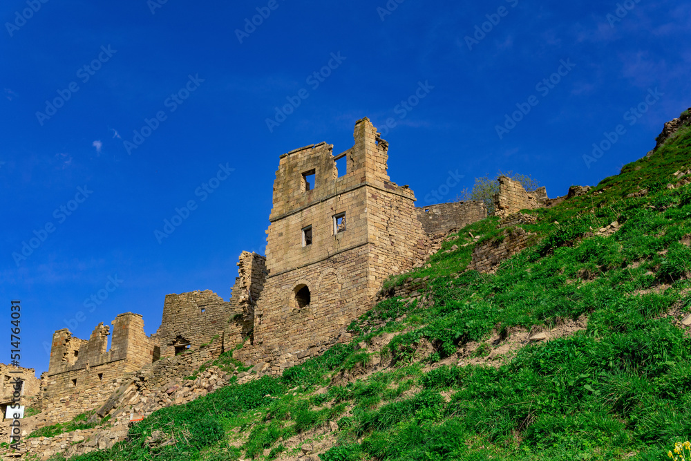 ruins of the walls of the houses against the sky in the depopulated village of Gamsutl in the sunset rays