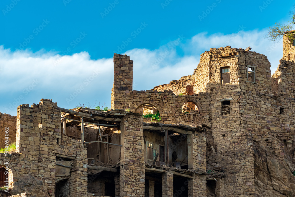 ruins of stone houses attached to the rock in the depopulated village of Gamsutl in Dagestan