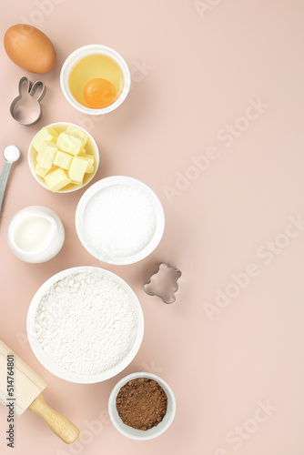 Baking ingredients and tools - flour  sugar  butter  eggs  cocoa  milk  baking powder  rolling pin  whisk  cookie cutters. Top view  copy space. Ingredients for cake  cookies  muffins.