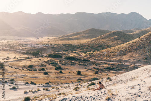 Woman sitting in a dune at sunset 