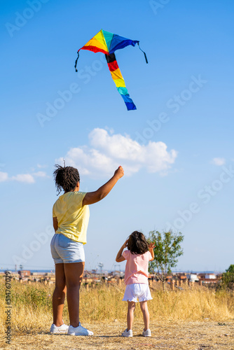 mother and daughter playing with a kite in the field