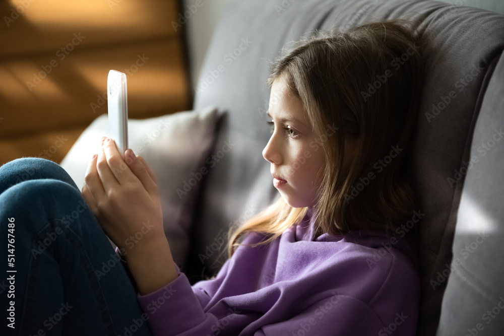 © irena_geo - Close up portrait of a Caucasian girl child looking at cell phone screen checking children content in social networks