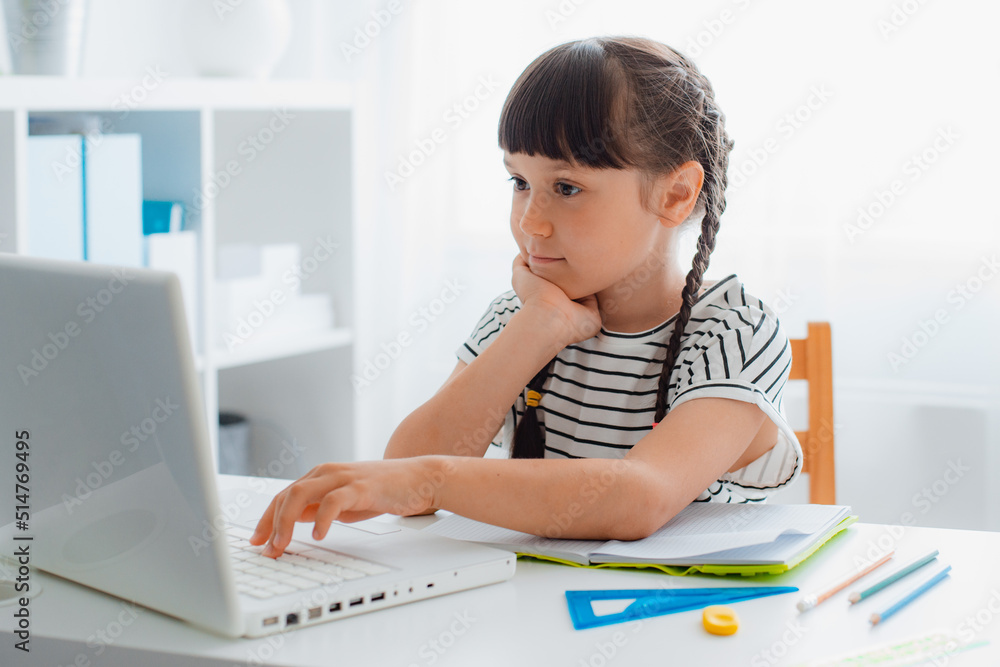 child of schoolchildren is a girl at home with a computer studying online, video call education. child of schoolchildren is a girl at home with a computer studying online, video call education.