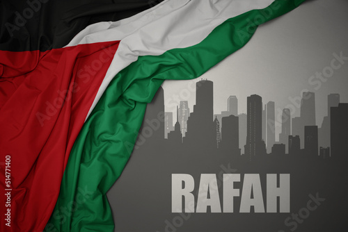 abstract silhouette of the city with text Rafah near waving national flag of palestine on a gray background.3D illustration photo