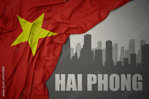 abstract silhouette of the city with text Hai phong near waving national flag of vietnam on a gray background.3D illustration