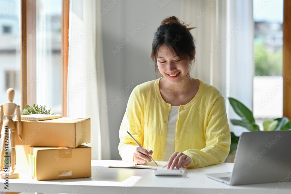 Young SME entrepreneur using calculator calculating financial expense at home office, Online marketing packaging delivery, Startup SME entrepreneur or Freelance woman concept. Young SME entrepreneur using calculator calculating financial expense at home office, Online marketing packaging delivery, Startup SME entrepreneur or Freelance woman concept.