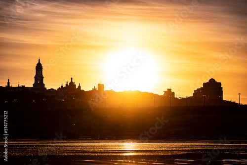 Beautiful Ukrainian sky with bright sub and city silhouette on background. Yellow color heaven.