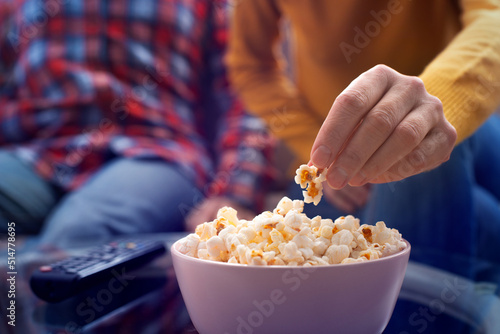Obraz na płótnie Caucasian couple sitting on sofa with popcorn and tv remote w salonie