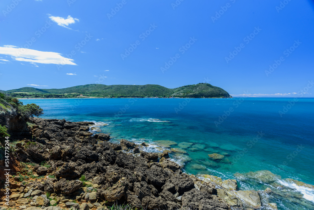 Felsküste von Barrati mit blauem Himmel und vereinzelten Wolken mit Blick auf Populonia Felsküste von Barrati mit blauem Himmel und vereinzelten Wolken mit Blick auf Populonia
