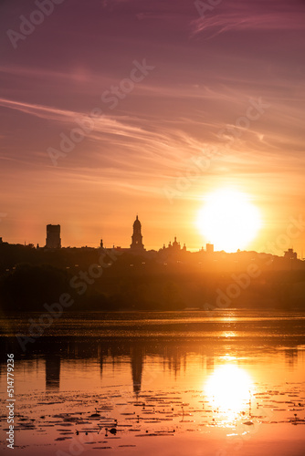 Beautiful Ukrainian sky with bright sub and city silhouette on background. Yellow color heaven.