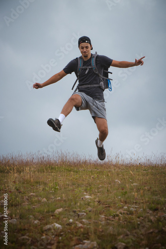 Swarthier type of man is running down a gravel hill, checking his every step to avoid injury. Active athlete runs over challenging terrain to improve fitness, coordination and precision of movement
