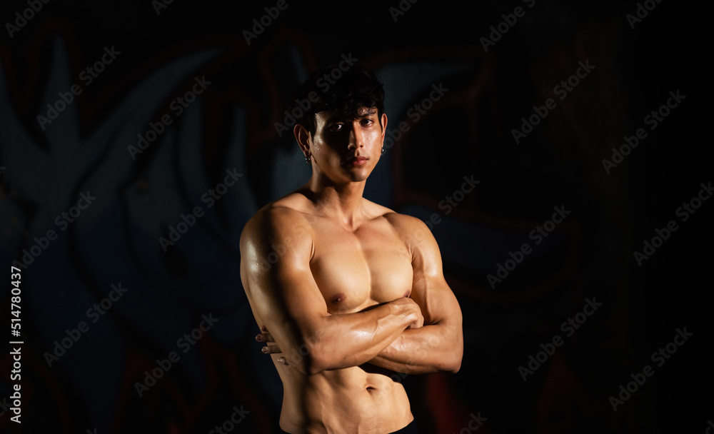Fototapeta premium Portrait of Shirtless strong Asian sportsman athlete do sport training workout exercise bodybuilding in abandoned building. Active man bodybuilder practicing muscular strength training in dark old gym