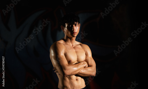 Portrait of Shirtless strong Asian sportsman athlete do sport training workout exercise bodybuilding in abandoned building. Active man bodybuilder practicing muscular strength training in dark old gym