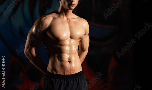 Portrait of Shirtless strong Asian sportsman athlete do sport training workout exercise bodybuilding in abandoned building. Active man bodybuilder practicing muscular strength training in dark old gym