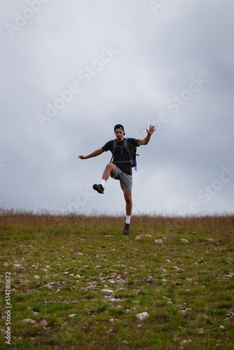 Swarthier type of man is running down a gravel hill, checking his every step to avoid injury. Active athlete runs over challenging terrain to improve fitness, coordination and precision of movement