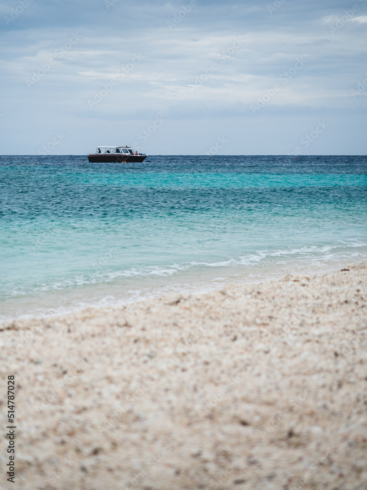 Scenic view of Koh Nang Yuan Island. Coral white sand beach with turquoise sea and faraway boat. Near Koh Tao Island, Surat Thani, Thailand. Selective focus, blurred beach foreground.