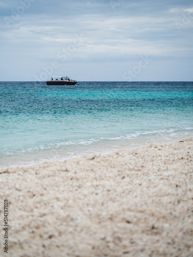 Scenic view of Koh Nang Yuan Island. Coral white sand beach with turquoise sea and faraway boat. Near Koh Tao Island, Surat Thani, Thailand. Selective focus, blurred beach foreground.