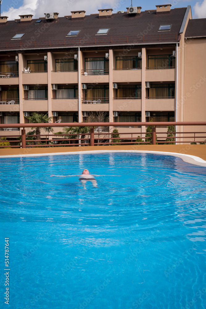 An elderly gray-haired retired man swims in the pool. The concept of a healthy active lifestyle in old age