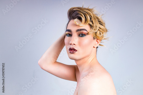 blond man with make up on face posing in studio on white background