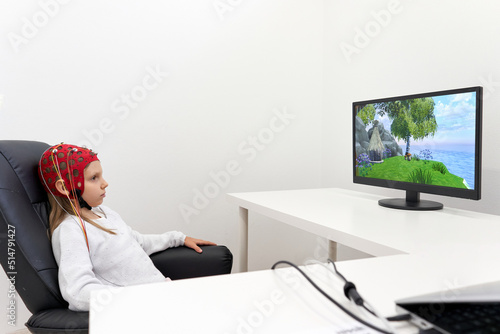 Girl looking to a screen while sitting on a chair during a biofeedback therapy photo
