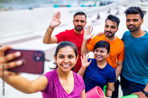 Photography four indian people warming up outdoors in sport wear making selfie on smartphone