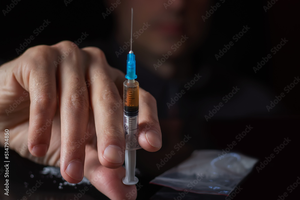 Drug syringe in hand. A drug addict with another dose of the drug in the syringe. Guy addicted - obrazy, fototapety, plakaty 