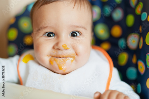baby feeding process. the first baby food. Little baby don't like food. messy face. Meal time. photo