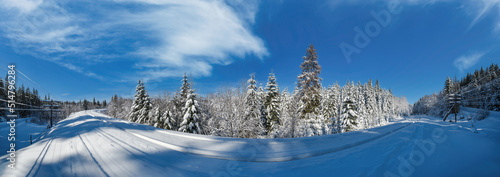 Railway through snowy fir forest and remote alpine helmet in Carpathian mountains, snow drifts on wayside