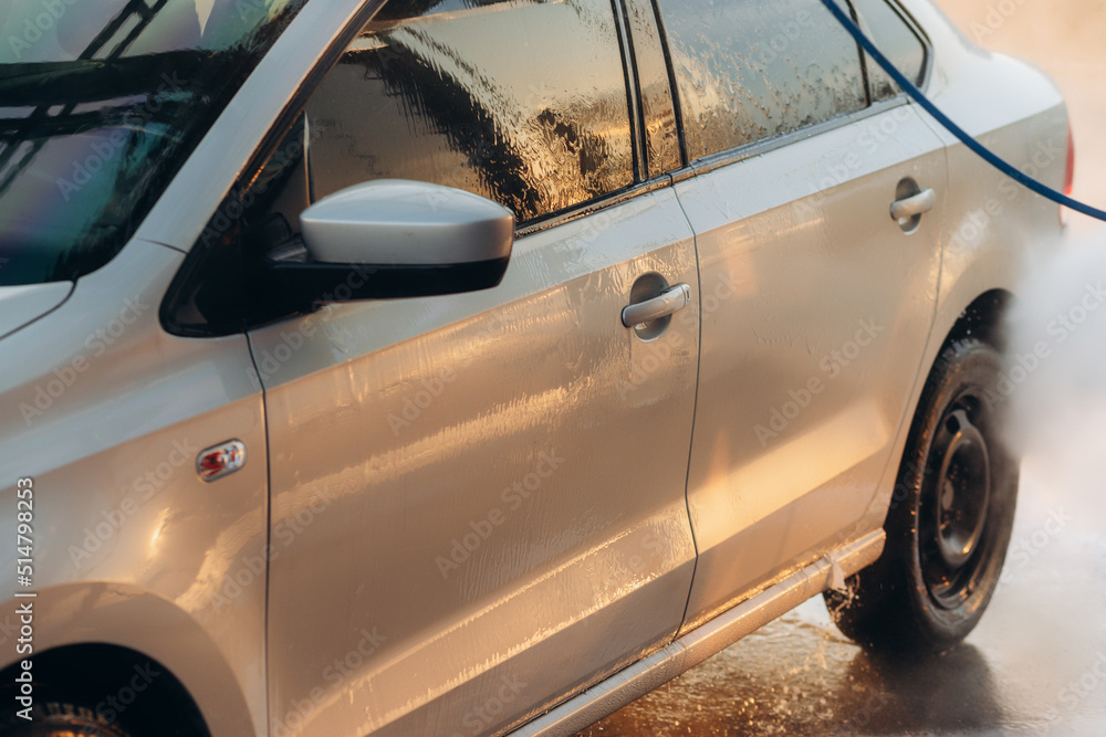 Close-up of a car under the water jet during the washing process on a self service car wash Close-up of a car under the water jet during the washing process on a self service car wash