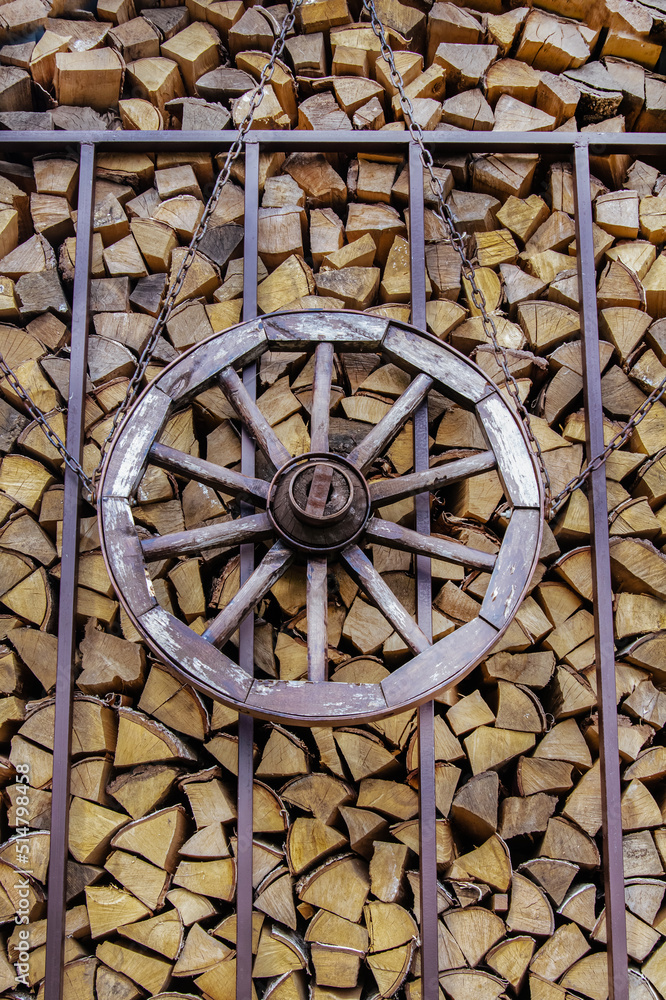 vintage wooden wheel on the background of a wooden woodpile of firewood