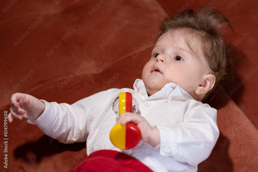 lying baby boy playing with a rattle lying baby boy playing with a rattle