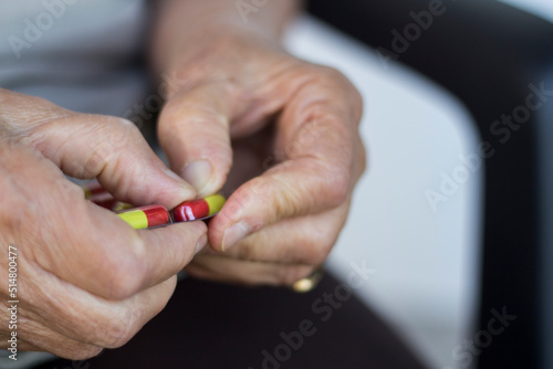 elderly woman holding pills. Old retired woman taking pills from a dispenser.