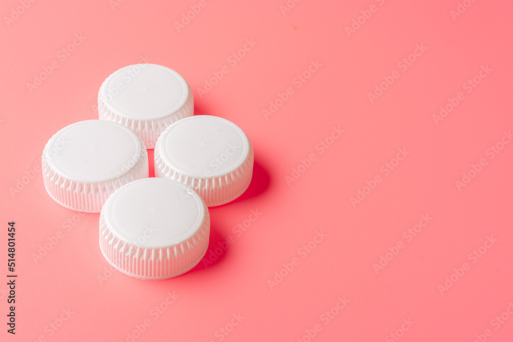 Obraz premium White bottles cap on light pink background.
