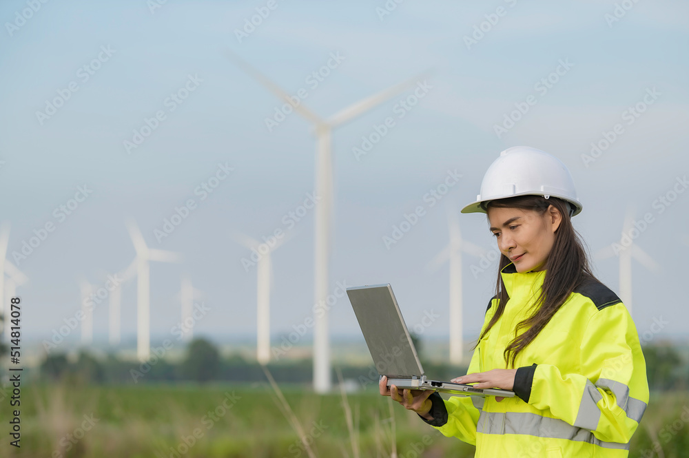 women engineer working and holding the report at wind turbine farm Power Generator Station on mountain,Thailand people women engineer working and holding the report at wind turbine farm Power Generator Station on mountain,Thailand people