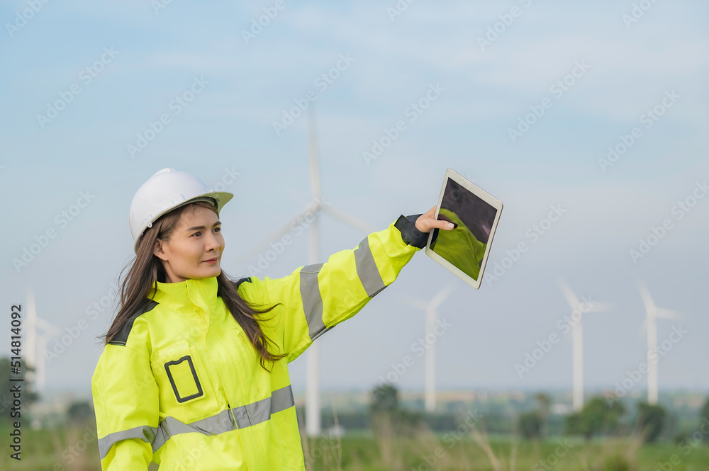women engineer working and holding the report at wind turbine farm Power Generator Station on mountain,Thailand people women engineer working and holding the report at wind turbine farm Power Generator Station on mountain,Thailand people