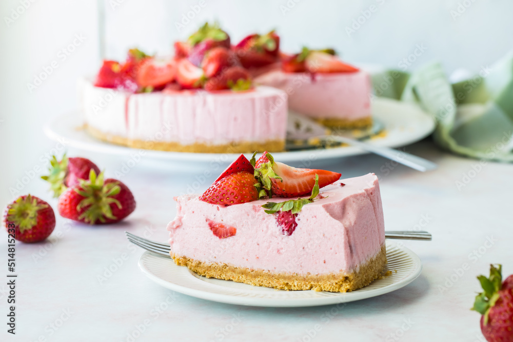 A slice of strawberry cheesecake with the rest of the cake in behind. A slice of strawberry cheesecake with the rest of the cake in behind.