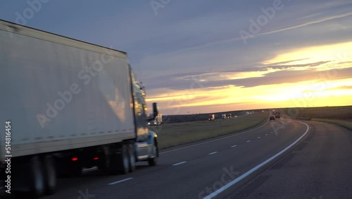A cargo container semi-trailer carrying goods driving on an empty interstate highway through prairie fields in texas, america. Trailer carrying cargo on a sunny morning