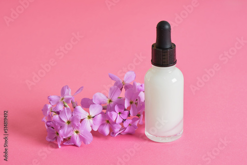 cosmetic serum for skin care in a transparent dropper bottle on bright pink background copy space top view mock up
