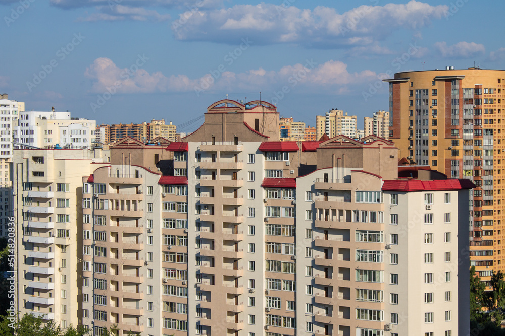 Urban landscape - modern multi-storey facades of houses on a sunny summer day and blue sky with clouds