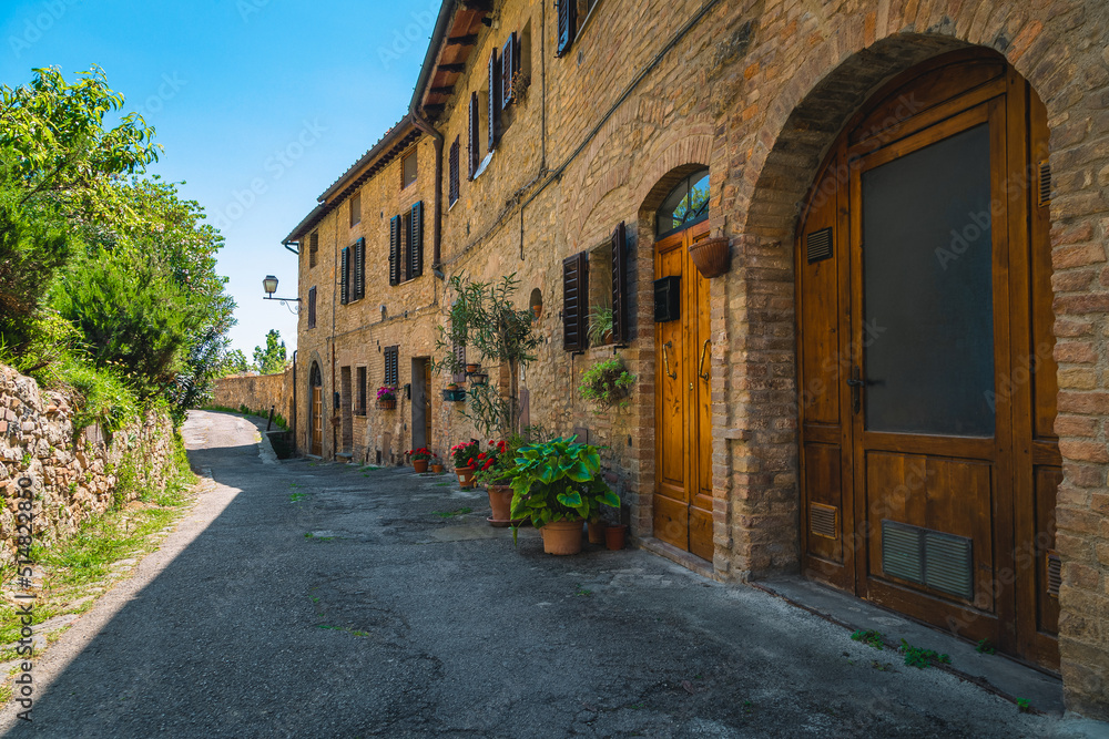 Brick houses and arranged street with flowers in San Gimignano