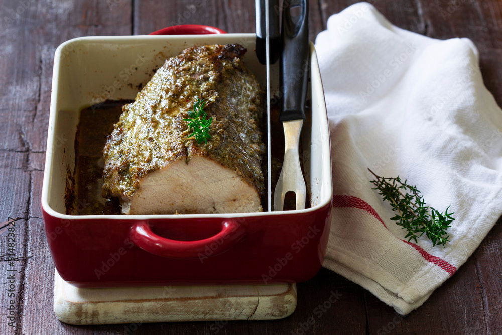 Pork loin baked with herbs, served in a baking dish. Rustic style.