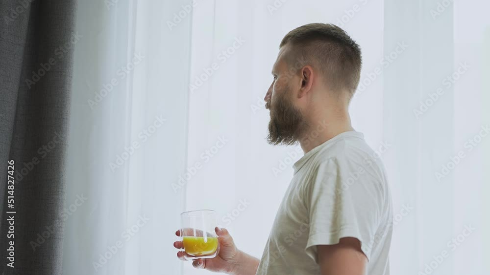 bearded man near the window drinking orange juice. simple nutritious breakfast. quench your thirst with a refreshing drink. citrus fruit. fresh squeezed orange juice bearded man near the window drinking orange juice. simple nutritious breakfast. quench your thirst with a refreshing drink. citrus fruit. fresh squeezed orange juice