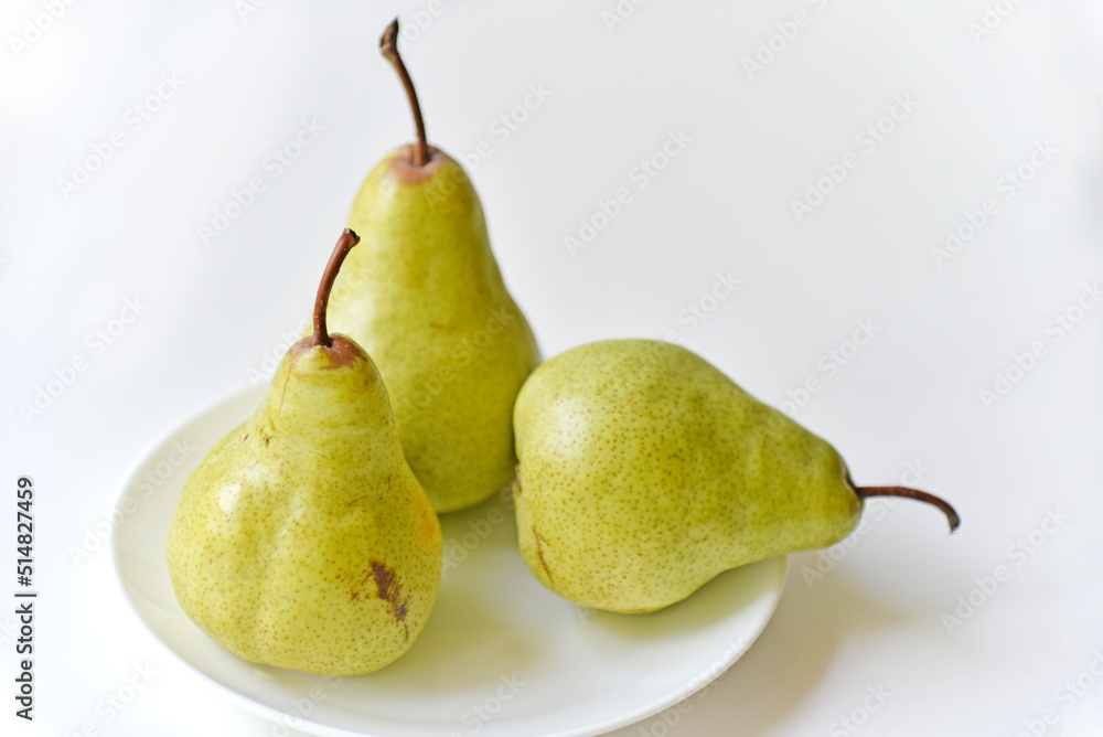 Green delicious pears on a white plate close-up Green delicious pears on a white plate close-up