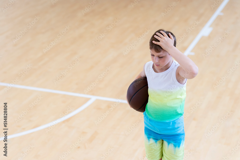 Sad disappointed boy with basketball ball in a physical education lesson Sad disappointed boy with basketball ball in a physical education lesson