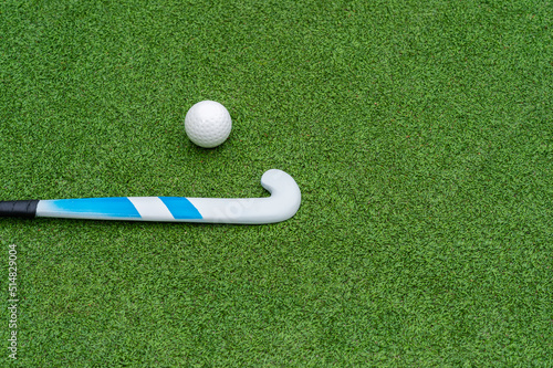 Field hockey stick and ball on green grass. Horizontal sport theme poster, greeting cards, headers, website and app.
